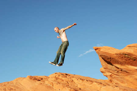 Man jumping off red rocksの写真素材