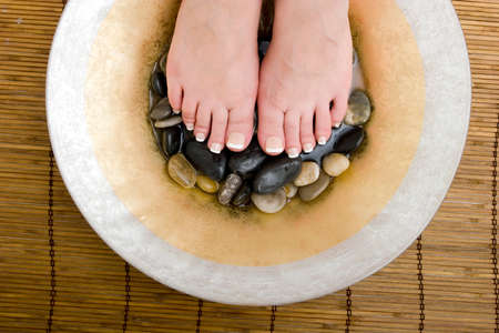 Woman's feet in bowl of water and rocksの写真素材