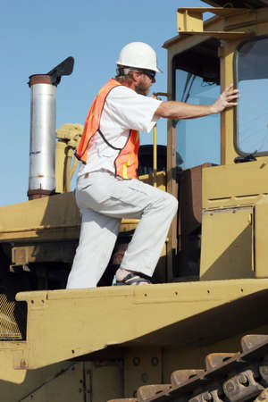 Construction worker climbing on the bulldozer