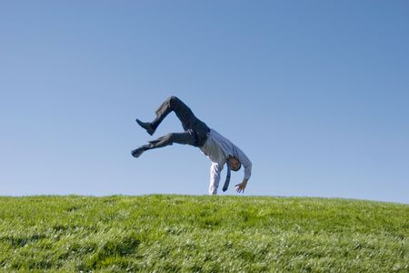 Happy businessman doing summersault on grassの写真素材