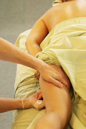 Massage therapist giving leg massage