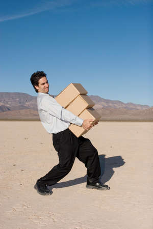 Businessman carrying heavy boxesの写真素材