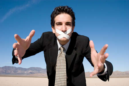 Businessman with a duct tape on his mouthの写真素材