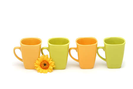 Colorful coffee mugs and daisy on isolated white backgroundの写真素材