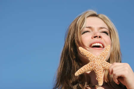 Beautiful sexy young woman holding a starfishの写真素材