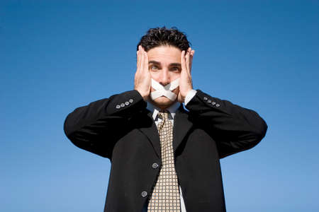 Businessman with a duct tape on his mouthの写真素材