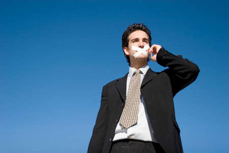 Businessman with a duct tape on his mouthの写真素材