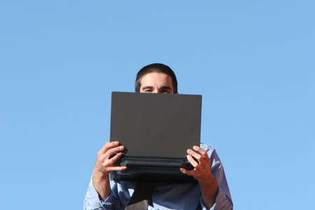 Businessman with his laptop against blue skyの写真素材