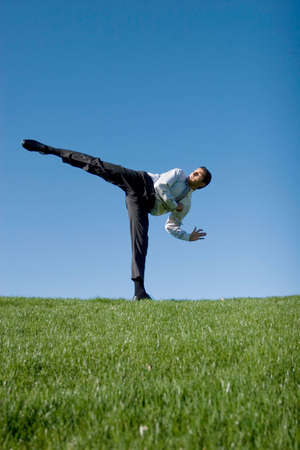 Businessman doing karate moves on green grassの写真素材