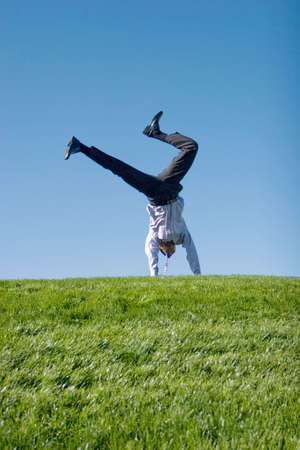 Happy businessman doing summersault on grassの写真素材