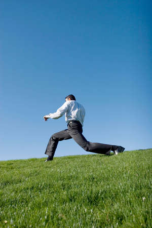 Businessman doing karate moves on green grassの写真素材