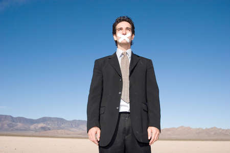 Businessman with a duct tape on his mouthの写真素材