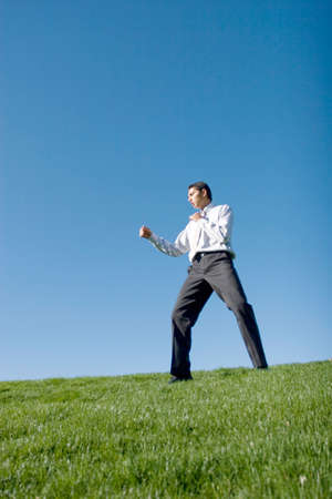 Businessman doing karate moves on green grassの写真素材