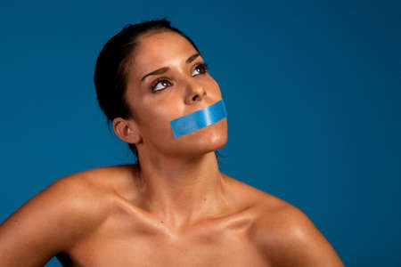 Woman with a duct tape over her mouthの写真素材