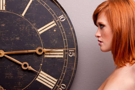 Beautiful young woman in front of an antique clock