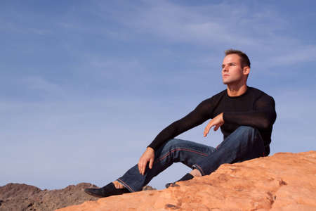 Stylish young man on red rocksの写真素材