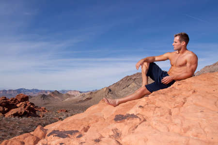 Athletic young man on red rocksの写真素材