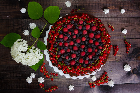 cake with red currants, raspberries and blackberries on a wooden backgroundの写真素材