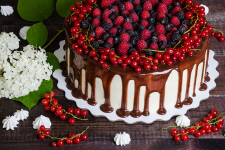 cake with red currants, raspberries and blackberries on a wooden backgroundの写真素材