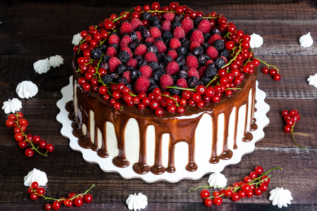 cake with red currants, raspberries and blackberries on a wooden backgroundの写真素材