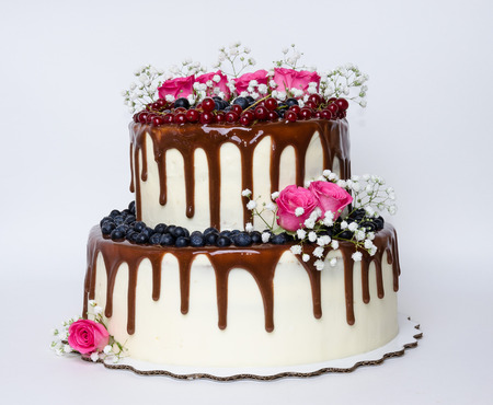 two layered color drip wedding cake with bilberries, red currants and rosesの写真素材