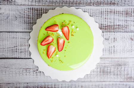 a mirror glaze mousse cake with strawberries and pistachios