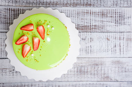 a mirror glaze mousse cake with strawberries and pistachiosの写真素材