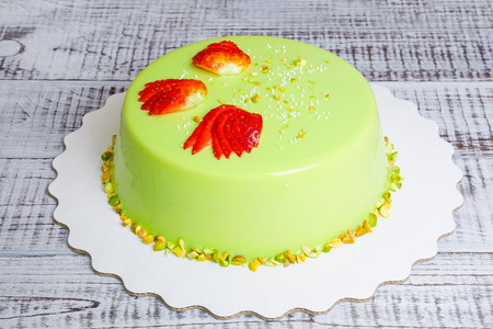 a mirror glaze mousse cake with strawberries and pistachiosの写真素材