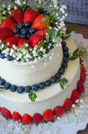 two-tier cream cheese wedding cake with blueberries and strawberriesの写真素材