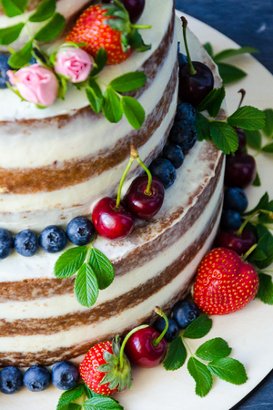 Naked wedding cake decorated with berries and flowersの写真素材