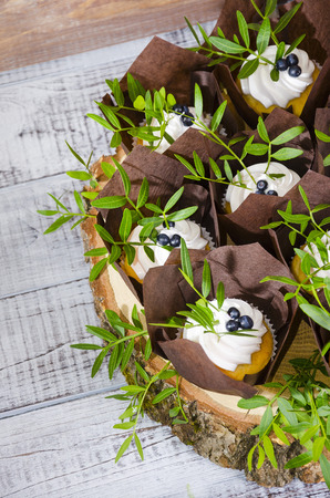 a wedding cake with topper and cupcakes decorated with greeneryの写真素材