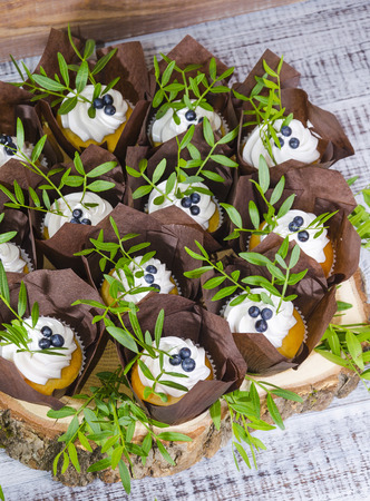 a wedding cake with topper and cupcakes decorated with greeneryの写真素材