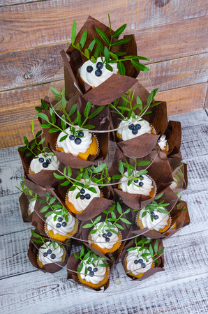 a wedding cake with topper and cupcakes decorated with greeneryの写真素材