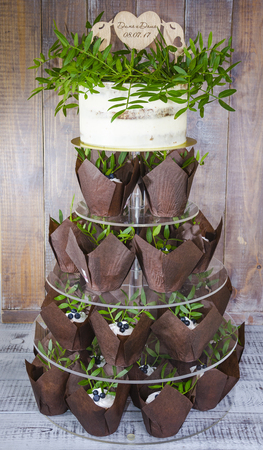 a wedding cake with topper and cupcakes decorated with greeneryの写真素材