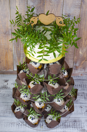 a wedding cake with topper and cupcakes decorated with greeneryの写真素材