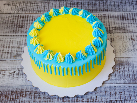 a yellow and blue cream cheese color drip cake with merenguesの写真素材