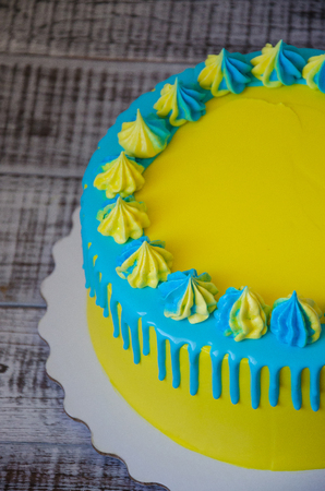 a yellow and blue cream cheese color drip cake with merenguesの写真素材