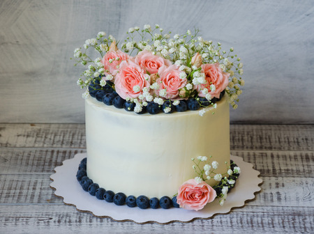 cream cake with gentle roses, greenery and juicy blueberriesの写真素材