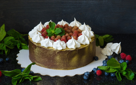 gilded chocolate cake with merengues, raspberries and mint leavesの写真素材