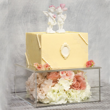 Exquisite two tiered chocolate wedding cake on glass box decorated with rosesの写真素材