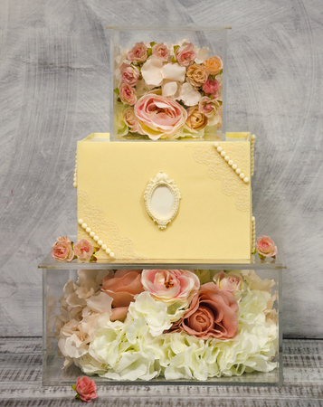Exquisite three tiered chocolate wedding cake on glass box decorated with rosesの写真素材