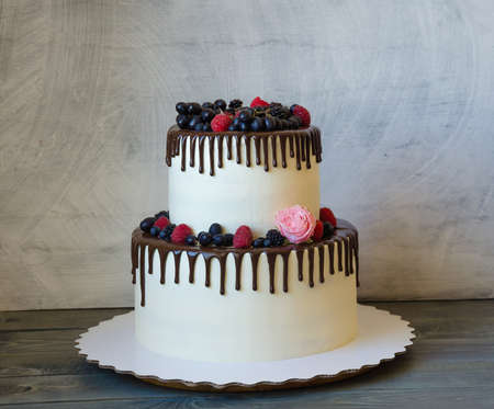 two tiered wedding cream cheese color drip cake with berriesの写真素材