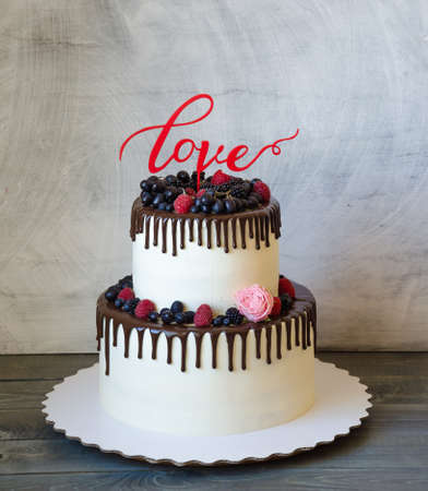 two tiered wedding cream cheese color drip cake with berriesの写真素材