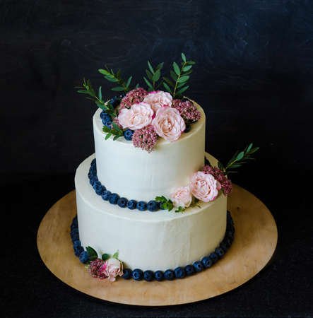 two tiered wedding cream cheese cake with roses and blueberriesの写真素材