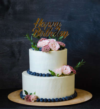 two tiered wedding cream cheese cake with roses and blueberriesの写真素材