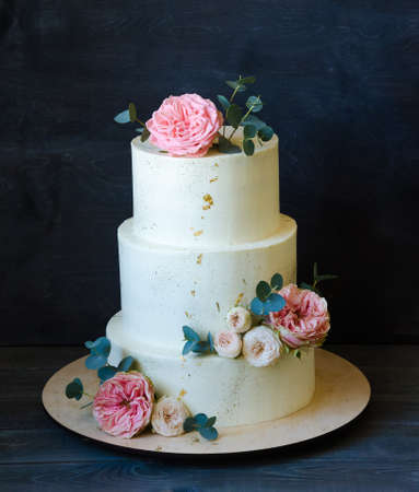 three tiered wedding cream cheese cake with roses and eucalyptusの写真素材