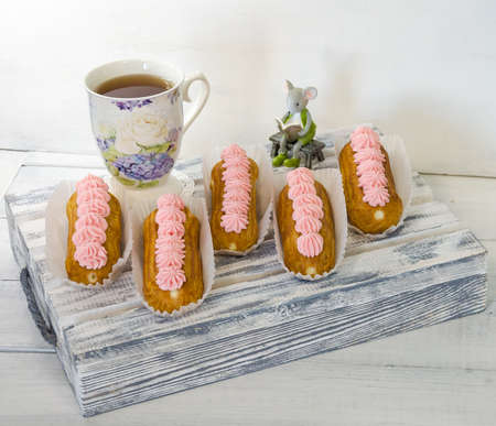 Yummy vanilla eclairs on wood with flower decoration