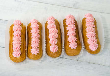 Yummy vanilla eclairs on wood with flower decorationの写真素材