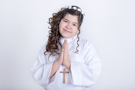 Little girl with curly hair posing for first communionの写真素材