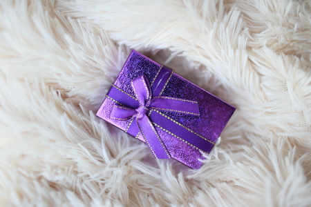 purple gift box on a light fur rugの写真素材